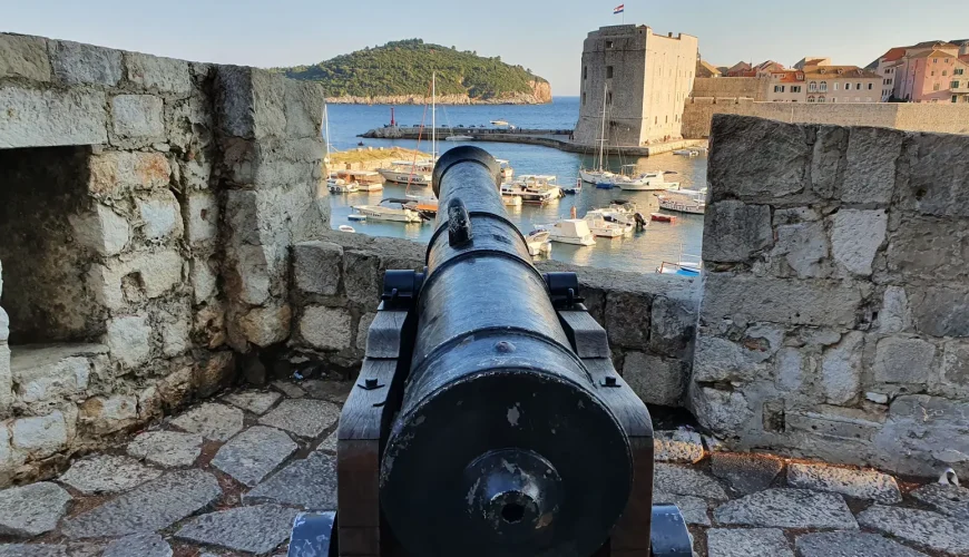 Old cannon on Dubrovnik's City Walls aimed over the Old Harbour at golden hour