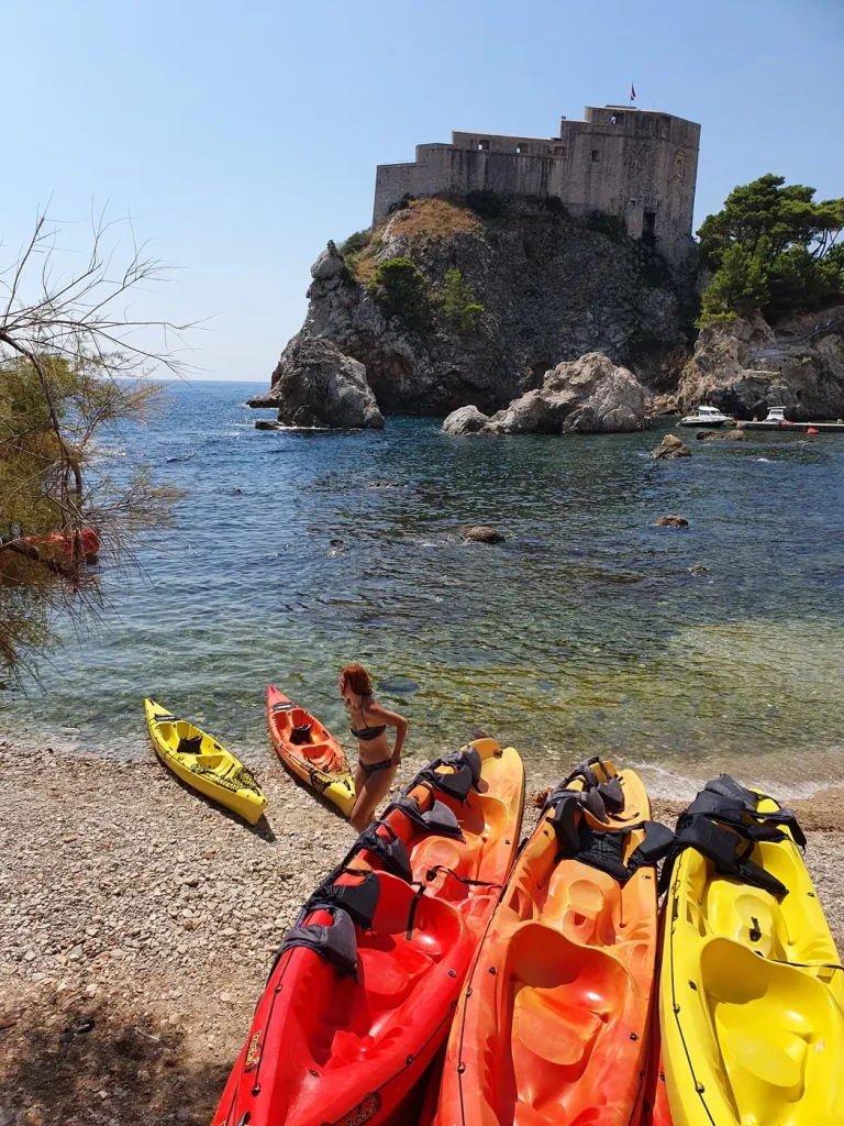 Colourful sea kayaks on the pebble beach below Fort Lovrijenac in Dubrovnik